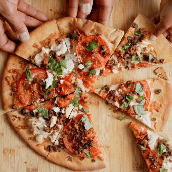 Animated image of hands grabbing pizza slices featuring Beyond Meat Crumbles